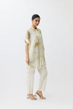 Load image into Gallery viewer, Woman wearing a light-colored outfit with floral patterns on a white background