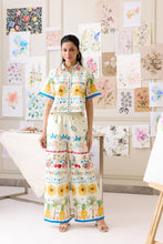 Load image into Gallery viewer, Woman in a colorful outfit standing in front of art displays