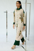 Load image into Gallery viewer, Woman wearing a cream and green outfit with floral patterns in front of a mirror.
